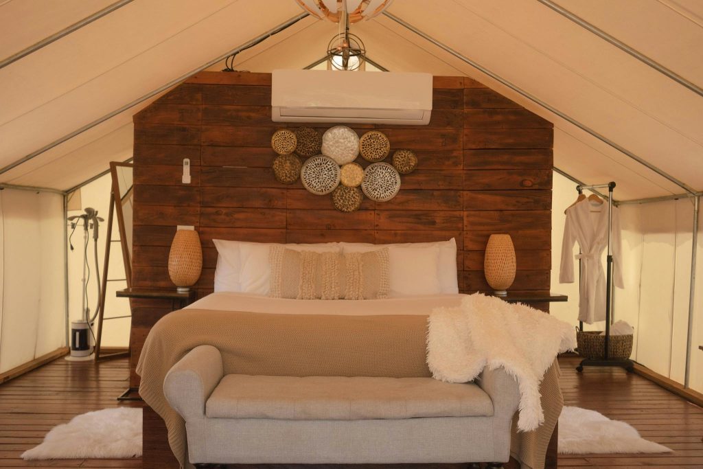 Elegant glamping tent featuring a beautifully designed bedroom with cozy textiles and rustic decor.